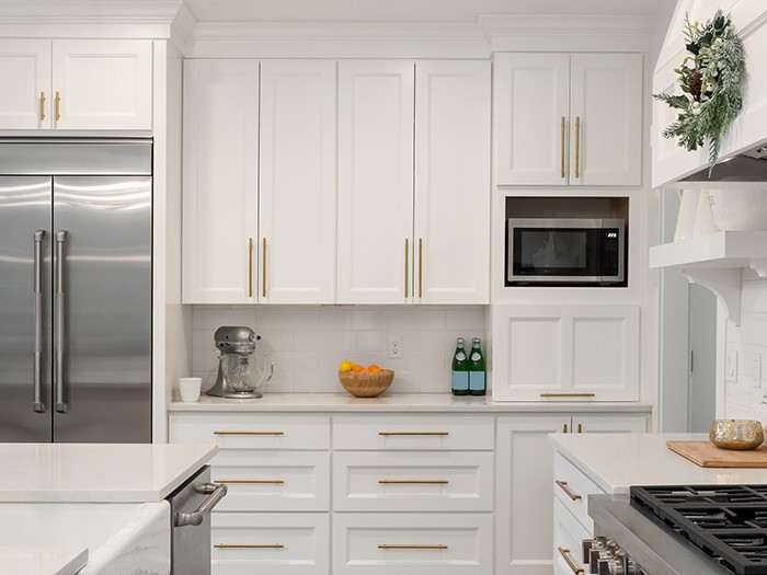 Small kitchen featuring white, ceiling-height cabinets.